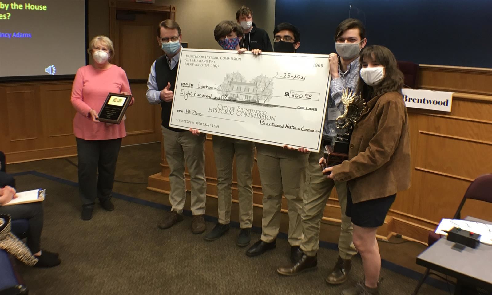 Centennial High students hold up a cardboard check 